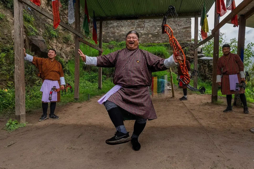 Bhutanese archers in traditional dress at a community event; the Sha Festival programme includes Sha-Gi-Dachham, an archery dance specific to Wangdue Phodrang