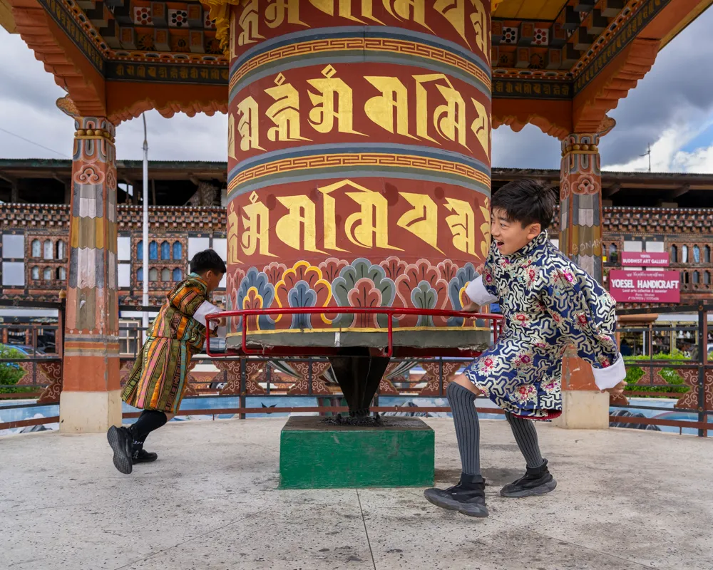 Large prayer wheel spinning at a Bhutanese monastery, generating merit and sending blessings into the flowing water below